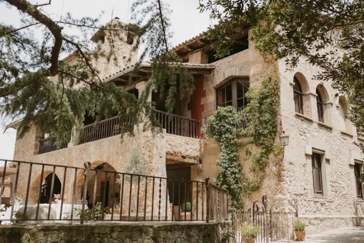 Fachada de Mas Vivencs con balcones de madera y hiedra